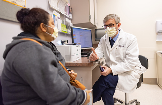 Male health care provider talking to female patient in clinic.