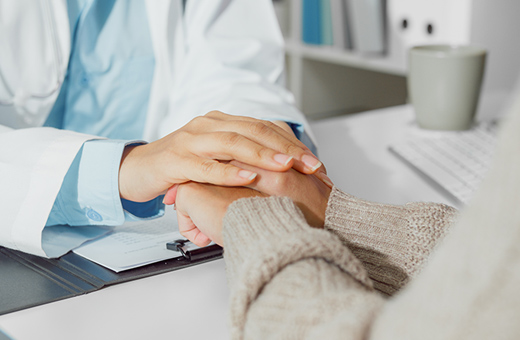Health care professional holding hands of patient before brain tumor surgery.