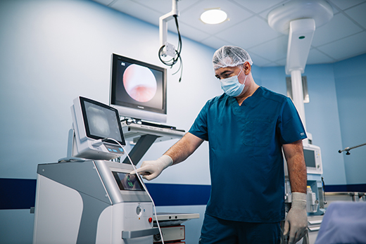 Male doctor in a mask, gloves, hair net and scrubs preparing for a colonoscopy