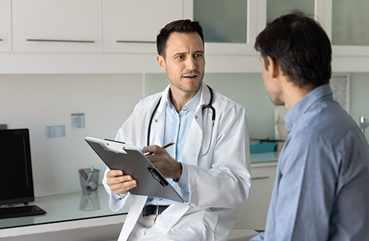Colorectal surgeon talking to male patient in clinic.