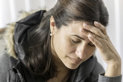 Woman holding her head with her eyes closed