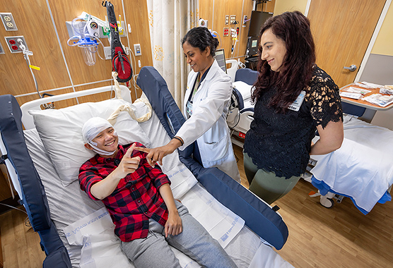 Male patient hooked up to an EEG monitor while doing a test with a two health care provider all smiling.