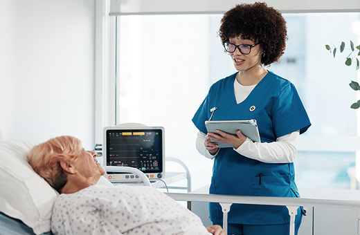 Patient in hospital bed talking to health care provider after GI surgery.