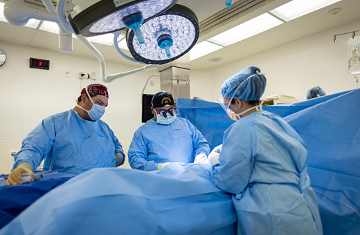 Surgeons performing gastrointestinal surgery on patient.