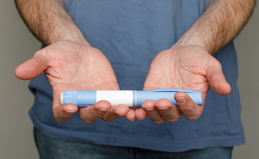 Man with open hands holding glp-1 medication tube.