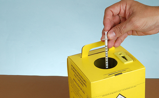 Needle disposal box with person putting glp-1 needle into box.