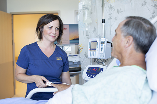 Female nurse looking down at a male patient in a hospital bed