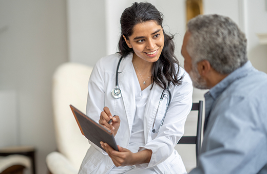 Female health care provider smiling and showing male patient some information on a mobile tablet