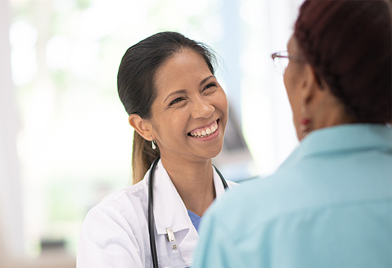 Female doctor smiling and touching the shoulder of a male patient.