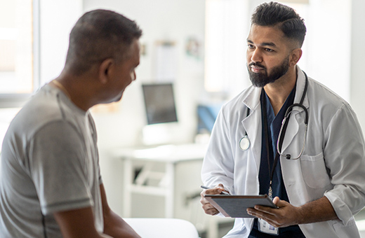 Male health care provider talking to male patient in a clinic.