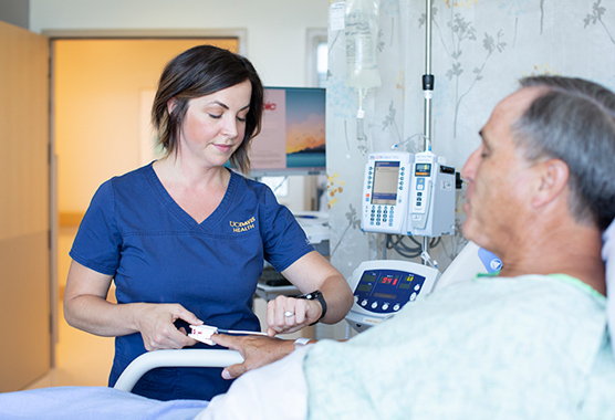 Female health care provider checking on male patient in a hospital bed.