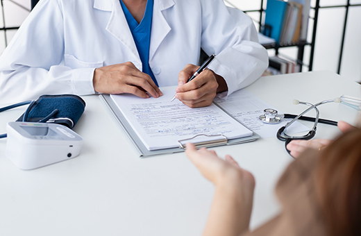 Orthopaedic surgeon writing in a notepad while talking with patient at a desk.