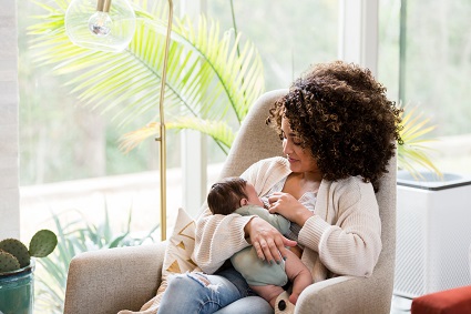 Woman sitting in a rocking chair while breastfeeding her baby