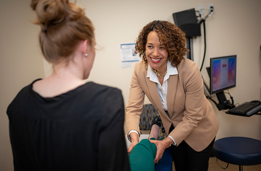 Physical therapist smiling at patient while working on her knee.