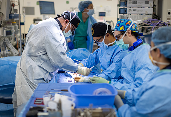 Surgeons using minimally invasive surgery techniques on patient in operating room.