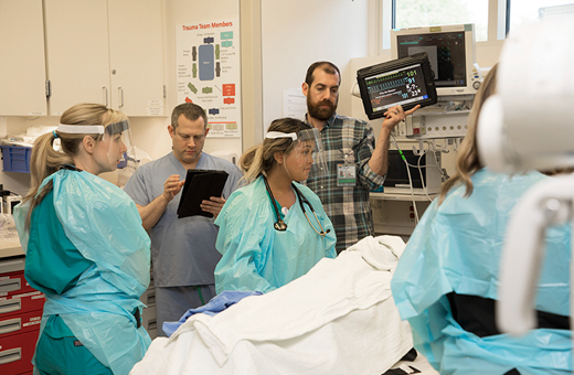 Health care professionals monitoring patient in trauma recovery.
