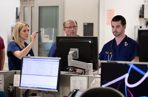Neurotrauama providers at computer screens discussing patient’s injuries.