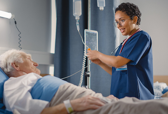 Health care provider taking care of patient in hospital bed.