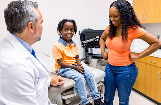 Mom and young boy in a clinic talking to a neurologist.