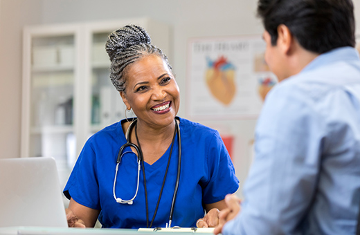 Health care provider smiling while speaking to a patient.