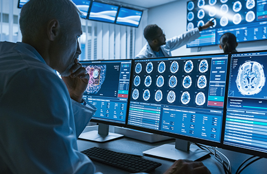 Over-the-shoulder shot of a medical provider reviewing brain scan images.