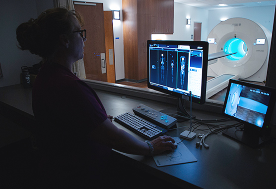 Female provider reviewing scans with an imaging machine in the background.