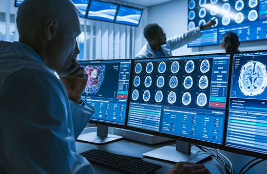 Over-the-shoulder shot of a male provider in a lab looking at brain images