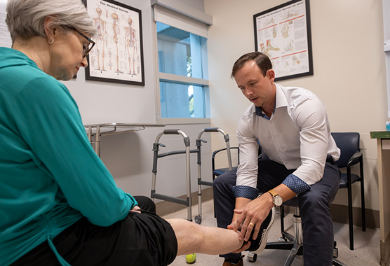 Orthopaedic surgeon examining a woman’s knee for a knee replacement.