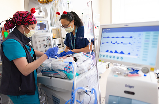 Health care providers caring for baby in NICU after pediatric neurosurgery.