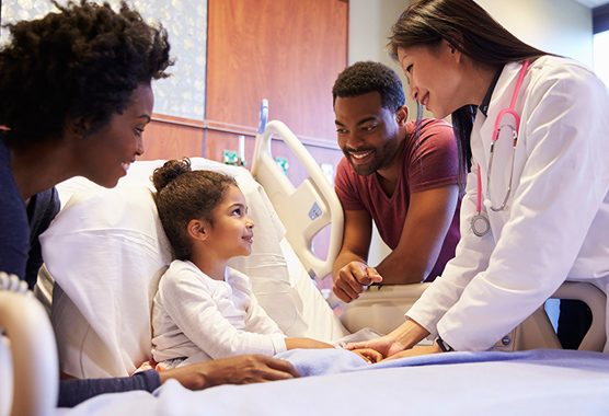Parents and health care provider smiling next to girl preparing for pediatric neurosurgery.