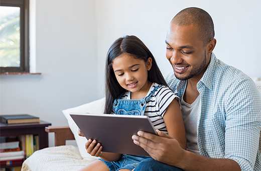 Young girl with her dad looking at a mobile tablet.