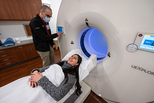 Woman smiling on the exam table after having a PET scan while provider stands next to her