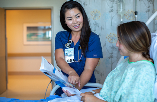 Female health care provider showing female patient some educational material in a hospital bed.