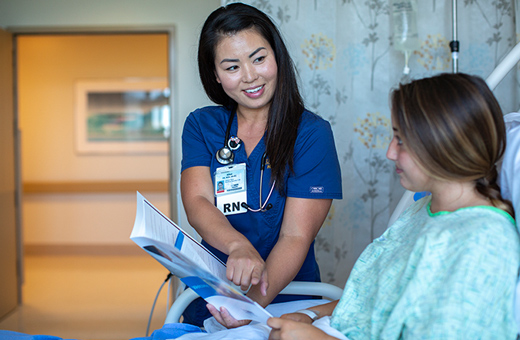 Nurse showing patient in hospital bed her follow-up care materials after spine neurosurgery.