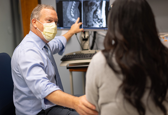 Spine surgeon discussing spine images with patient ahead of spine neurosurgery.