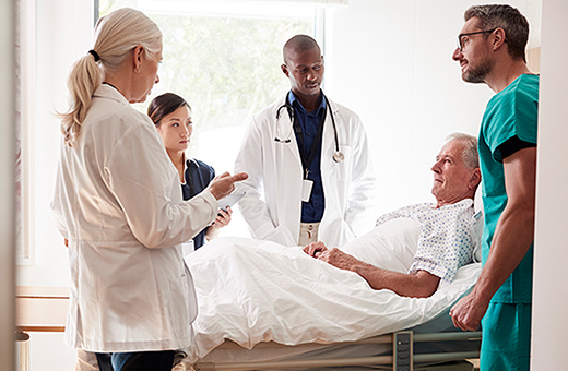 Health care team talking with male patient in hospital.