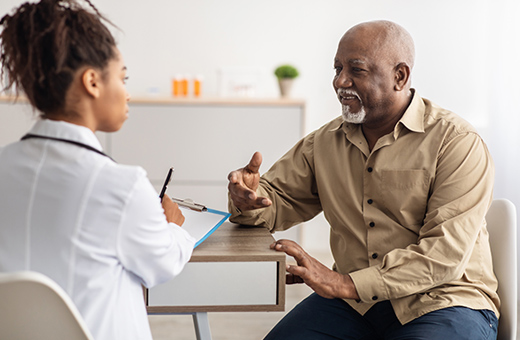 Male patient talking to female health care provider at a desk.