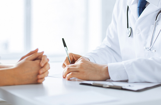 Health care provider talking to patient about thoracic surgery while sitting at a table with paperwork.