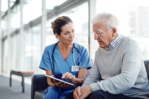 Female health care provider talking to older male patient in a waiting room