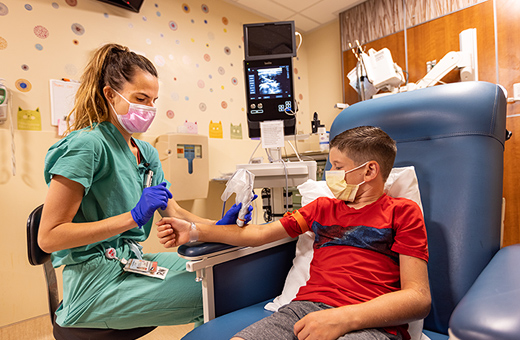 Young boy sitting in a chair getting an ultrasound on his forearm by a female technician.