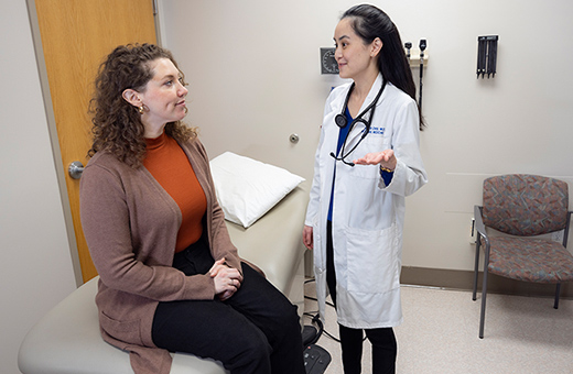 Female patient sitting on a clinic table talking to a female health care provider.