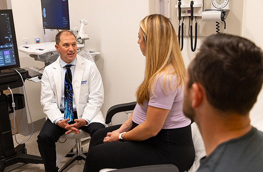 OB-GYN specialist talking with pregnant woman and her husband in a clinic.