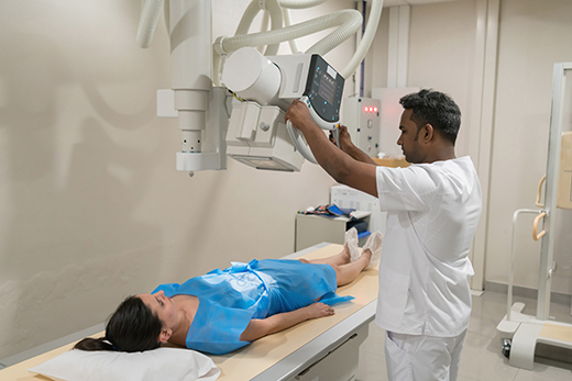 Woman standing facing a wall while x-ray happens