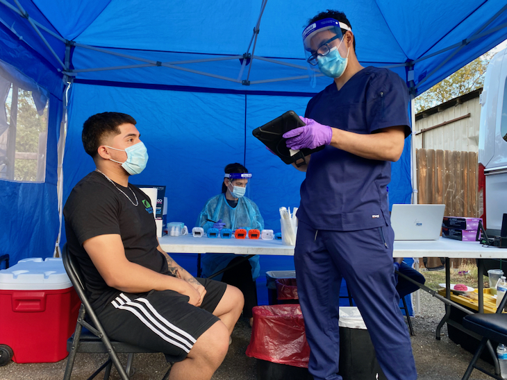 Conrad Preciado of UC Davis Health speaks with Brandon Lopez in preparation of Lopez’s COVID-19 test in Knights Landing