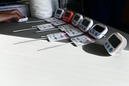 COVID-19 swab samples lay on a table next to portable timers that are set for 15 to 20 minutes to await test results 