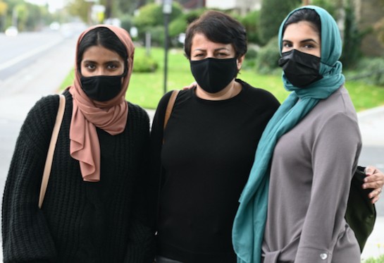 Students Sasha Afroz, Niloofar Jannesar and Maha Kazmi on the sidewalk before visiting the home of a refugee family