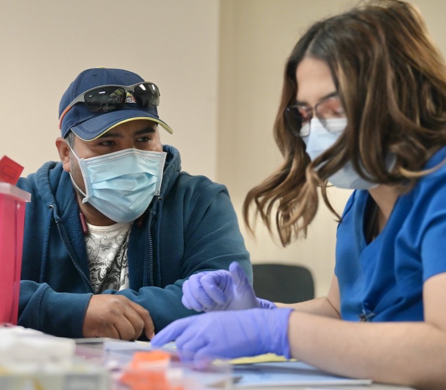 Worker in baseball cap Antonio González, 37, gets his COVID-19 booster shot in the office of Pamukey Yolo Vineyard near Esparto