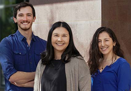 Assistant Professor Megan Dennis and graduate students Colin Shew and Daniela Soto stand outside the UC Davis Genome Center.