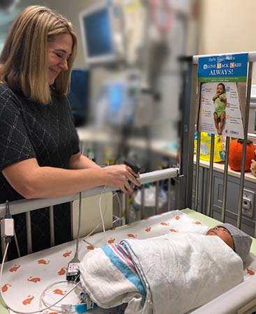 Doctor in NICU looks over baby in crib