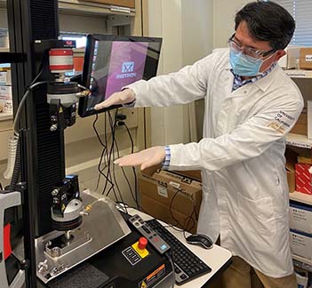 Dr. Aijun Wang in his lab wearing a white lab coat. 